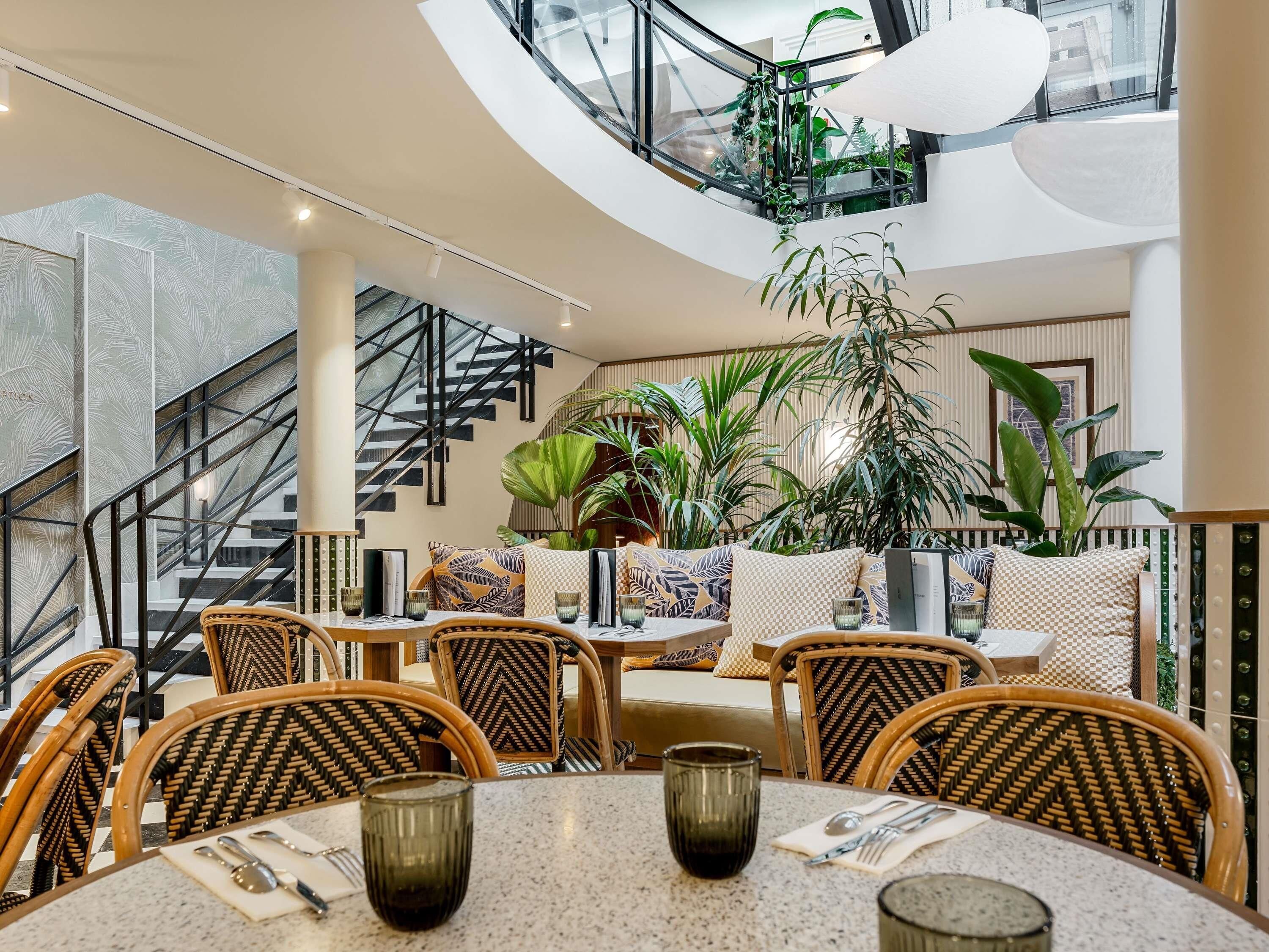 A modern interior with a dining area, staircase, and large windows.