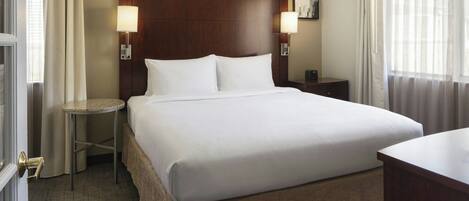 A hotel room with a large bed, two bedside tables, a nightstand, and a desk.