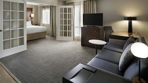Une chambre d’hôtel avec un lit, un canapé, une télévision, un bureau et une lampe.