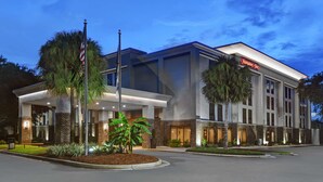 A modern hotel with a 'Welcome' sign, a flag, and a 'Hampton Inn' sign. - Hampton Inn Charleston/Mount Pleasant-Patriots Point (Mount Pleasant)