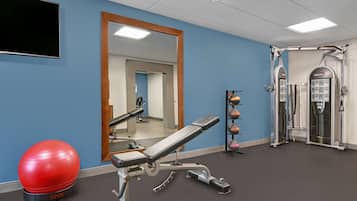A gym with exercise equipment, a red exercise ball, and a mirror on the wall.