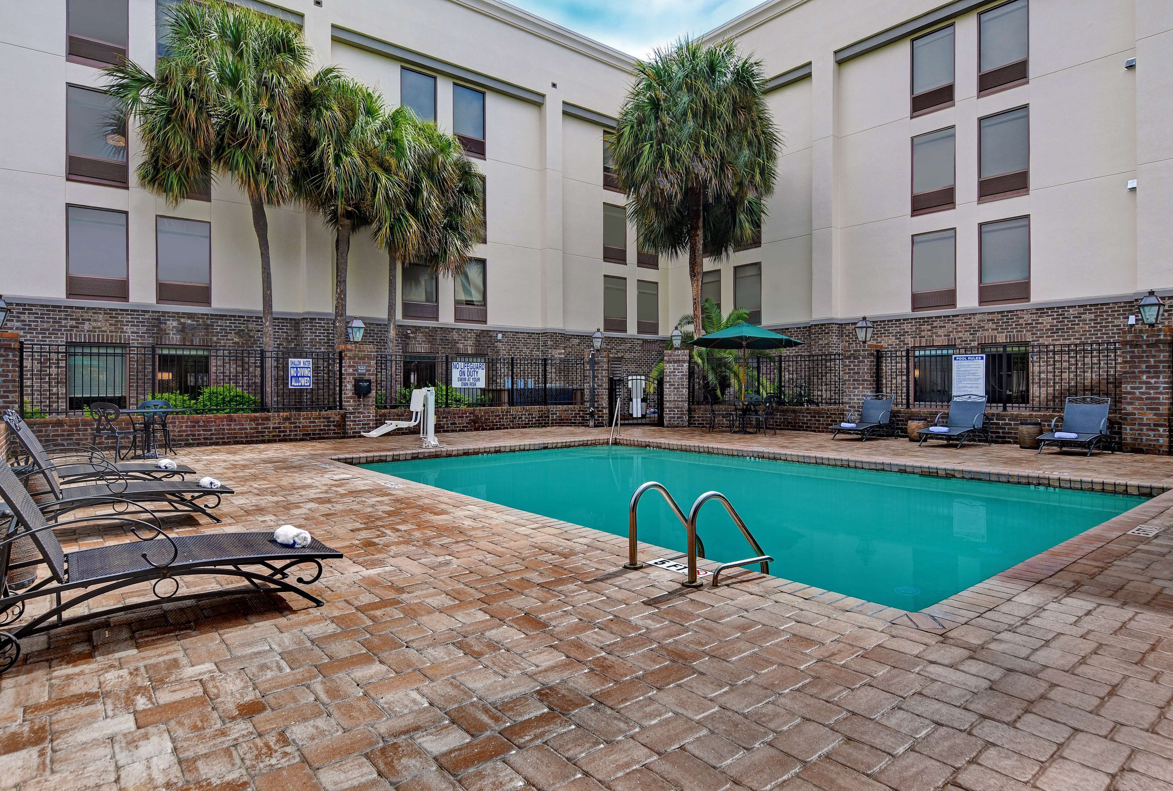 A pool area with lounge chairs and a brick patio.