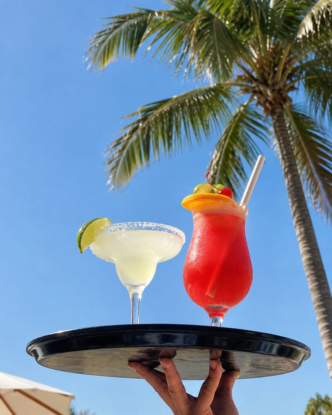 A tray with two cocktails, one red and one white, held by a person.