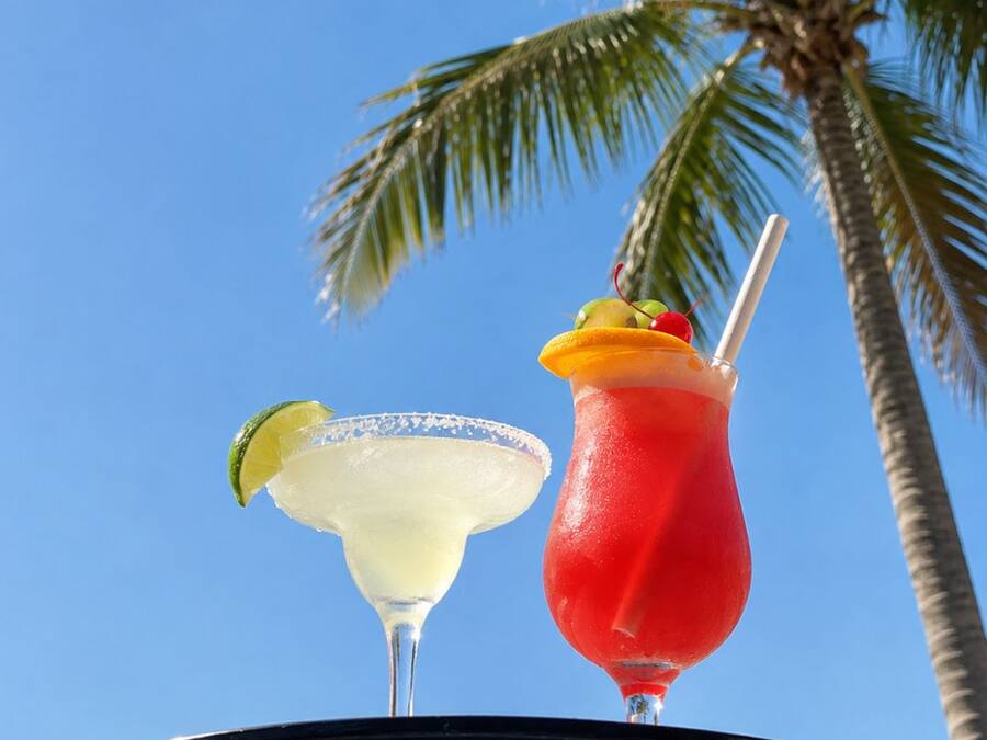A tray with two cocktails, one red and one white, held by a person.