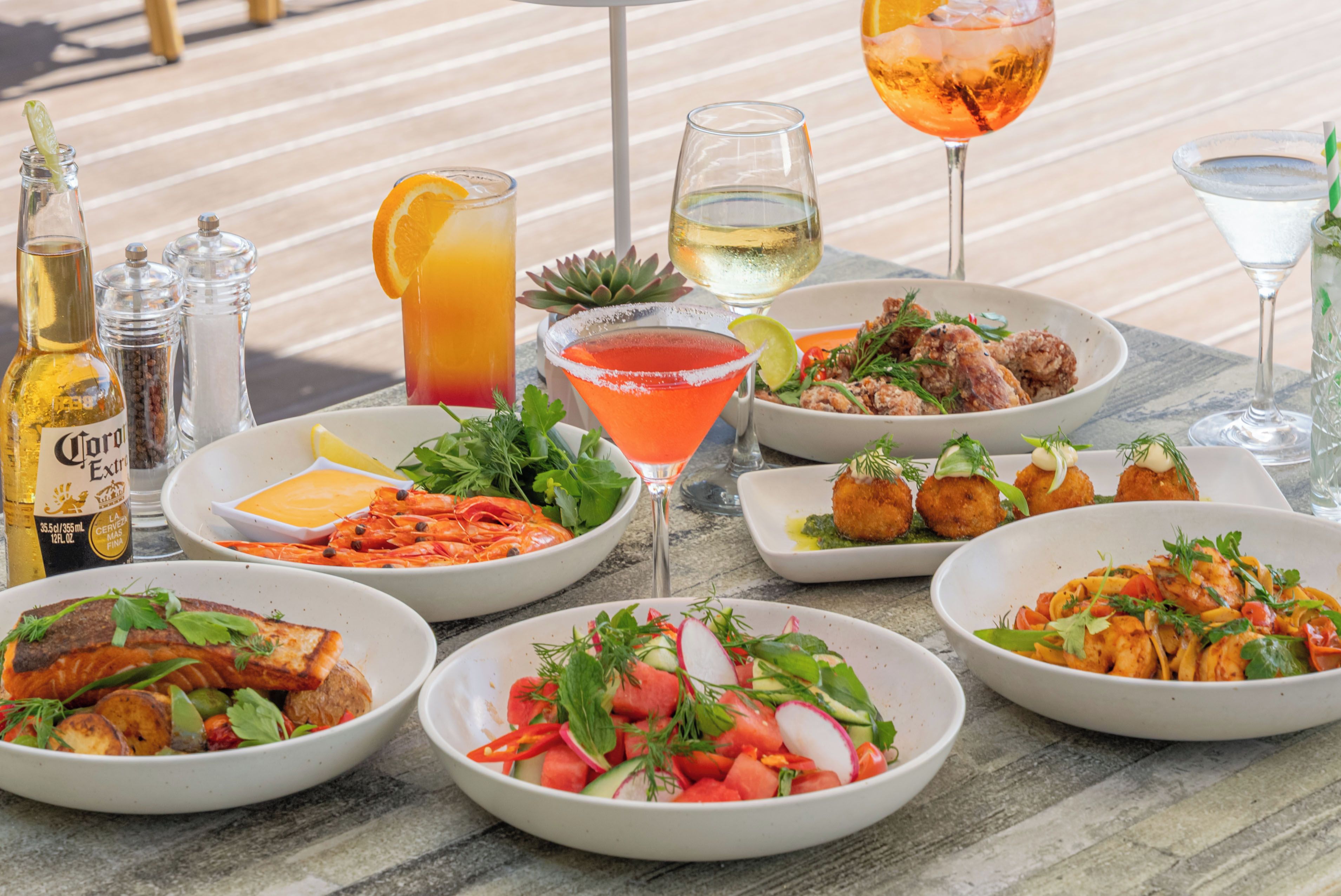 Una mesa dispuesta con diversos platos, bebidas y acompañamientos, lo que sugiere una experiencia gastronómica.