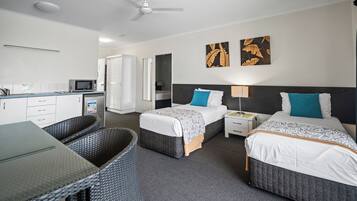 Een hotelkamer met twee bedden, een zithoek en een kitchenette.