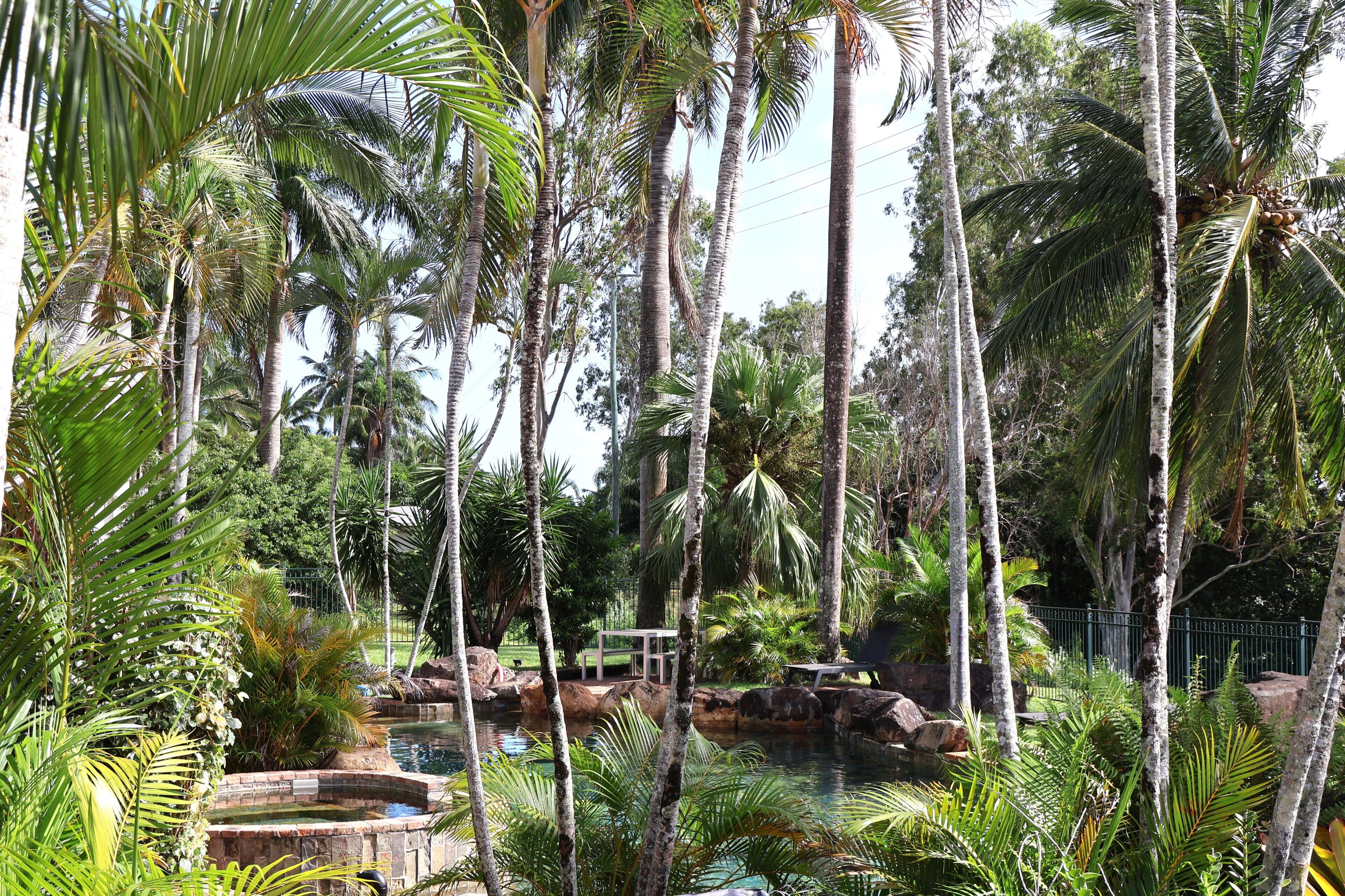 A tropical resort with a pool, palm trees, and a gazebo.