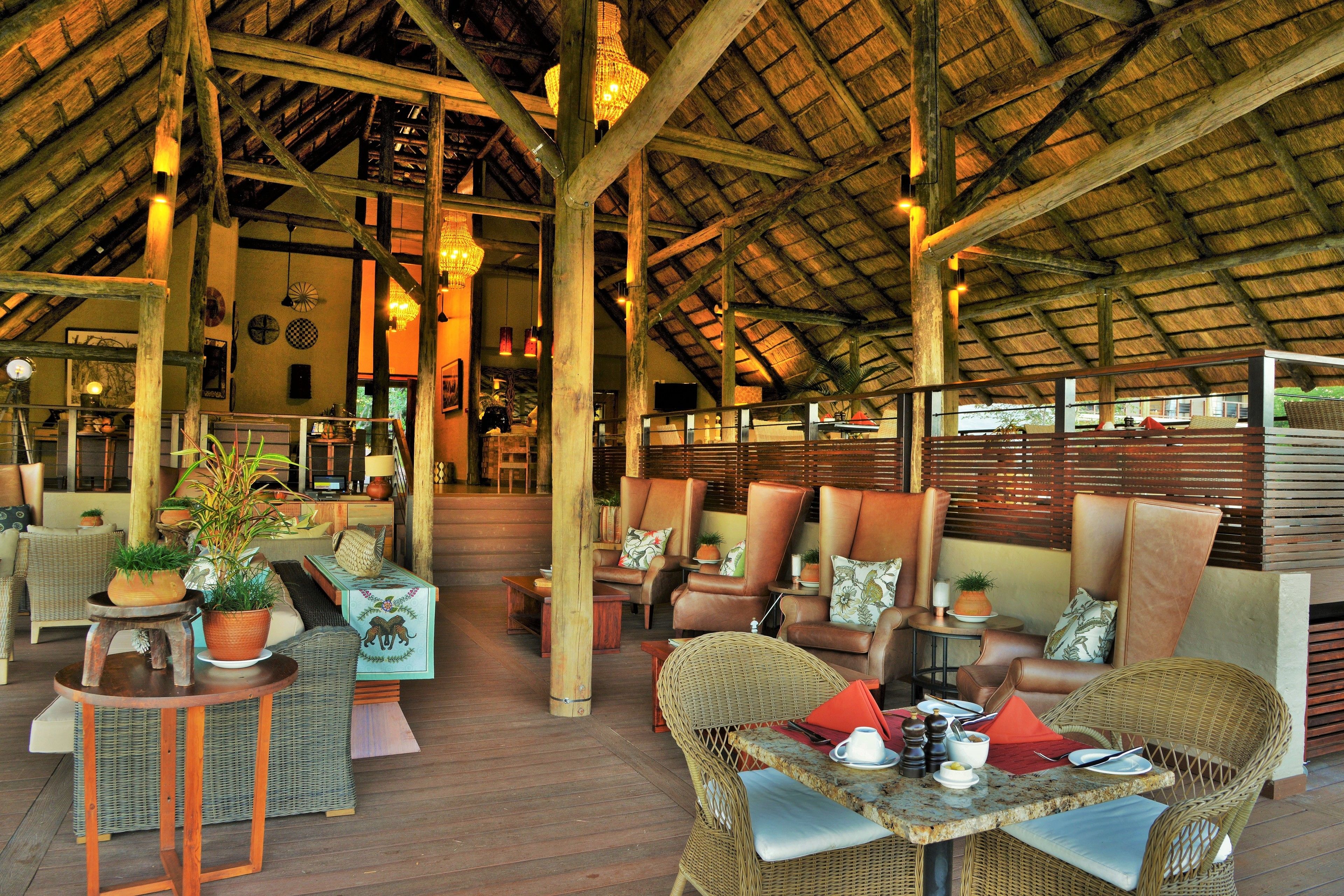 An indoor seating area with wicker furniture, wooden beams, and hanging lights.