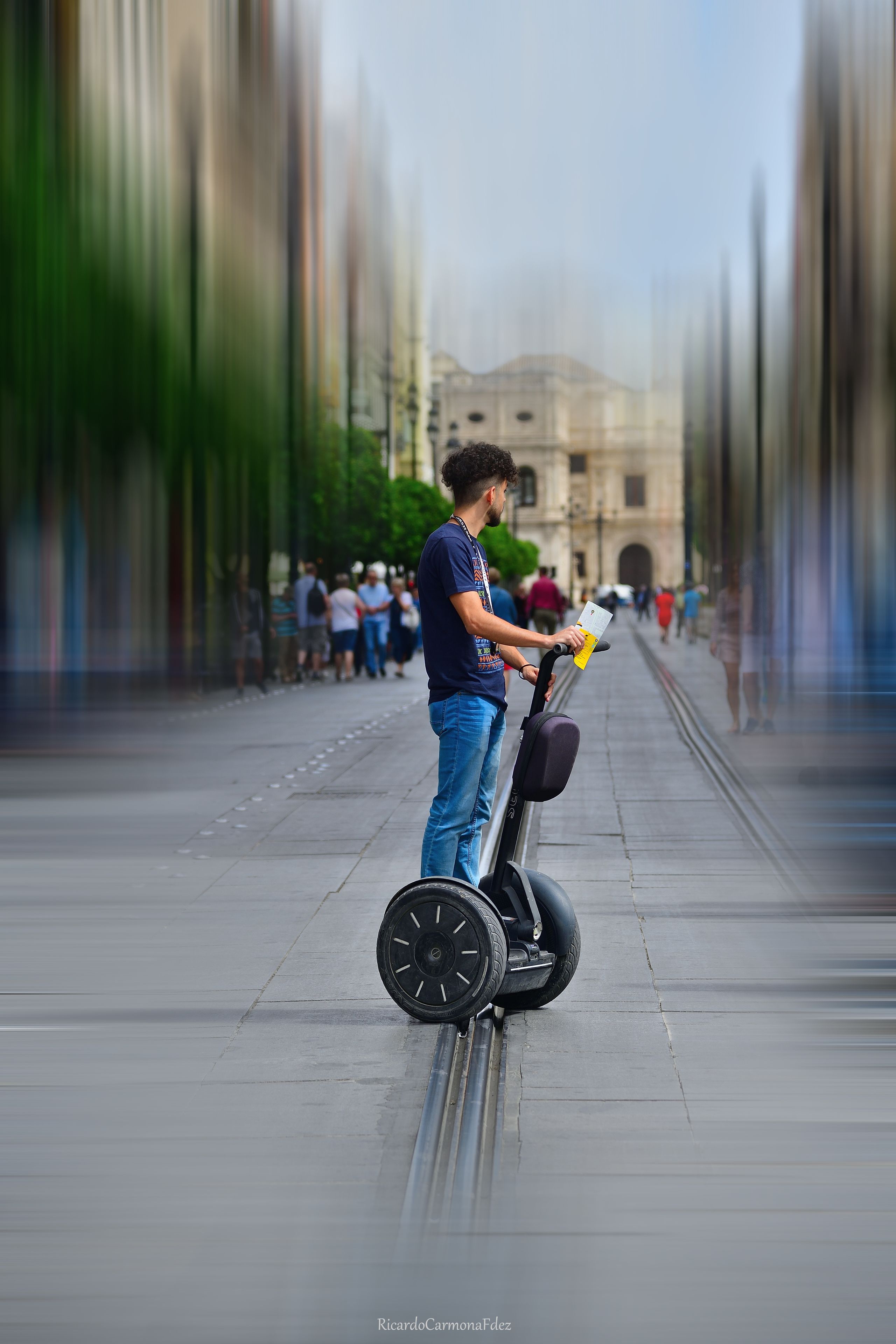 Una persona circulando en un Segway por una acera ancha y recta.