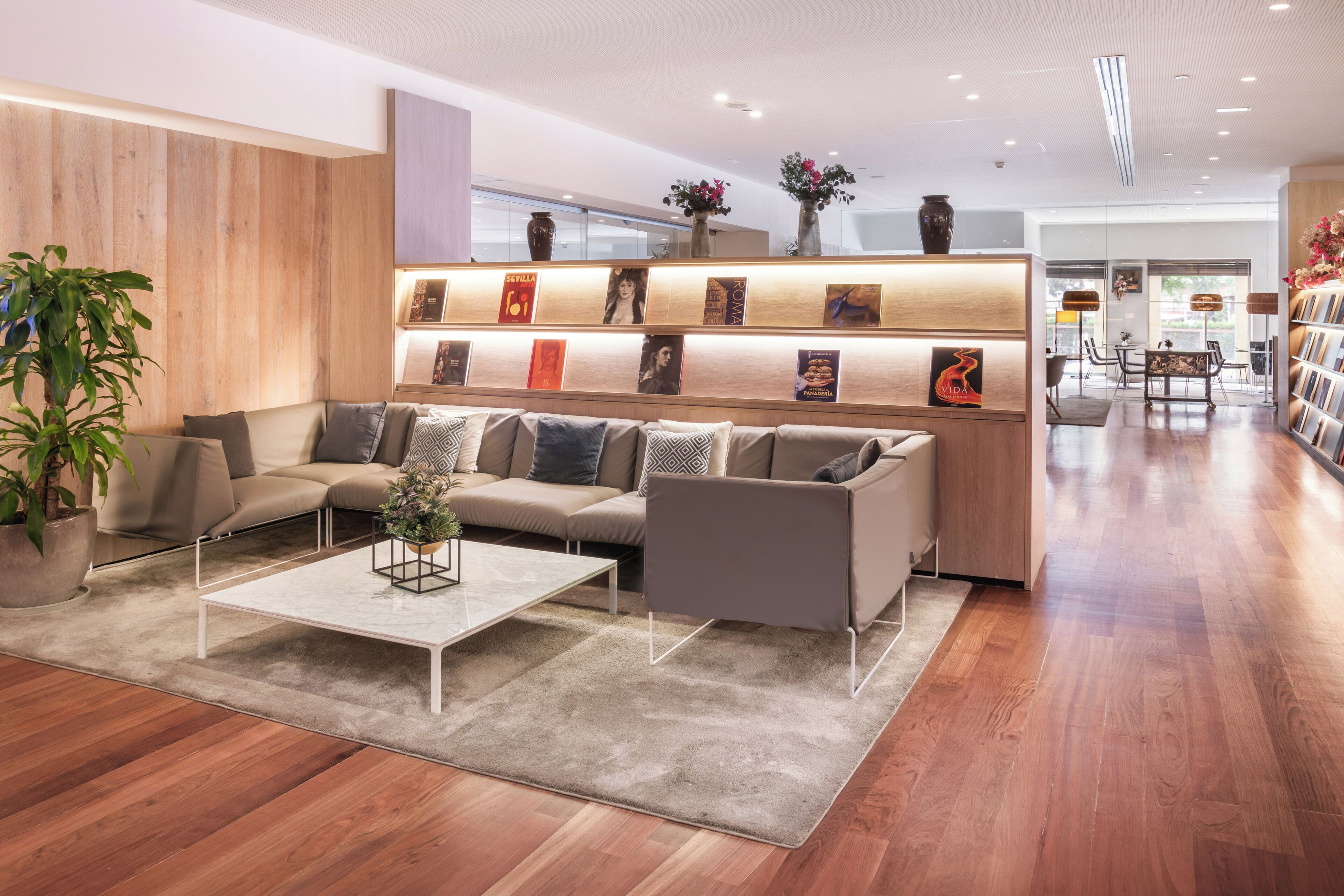 A modern lounge area with a sofa, coffee table, and a bookshelf with books and decorative items.