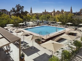 Una piscina al aire libre, sombrillas, sillones reclinables de piscina