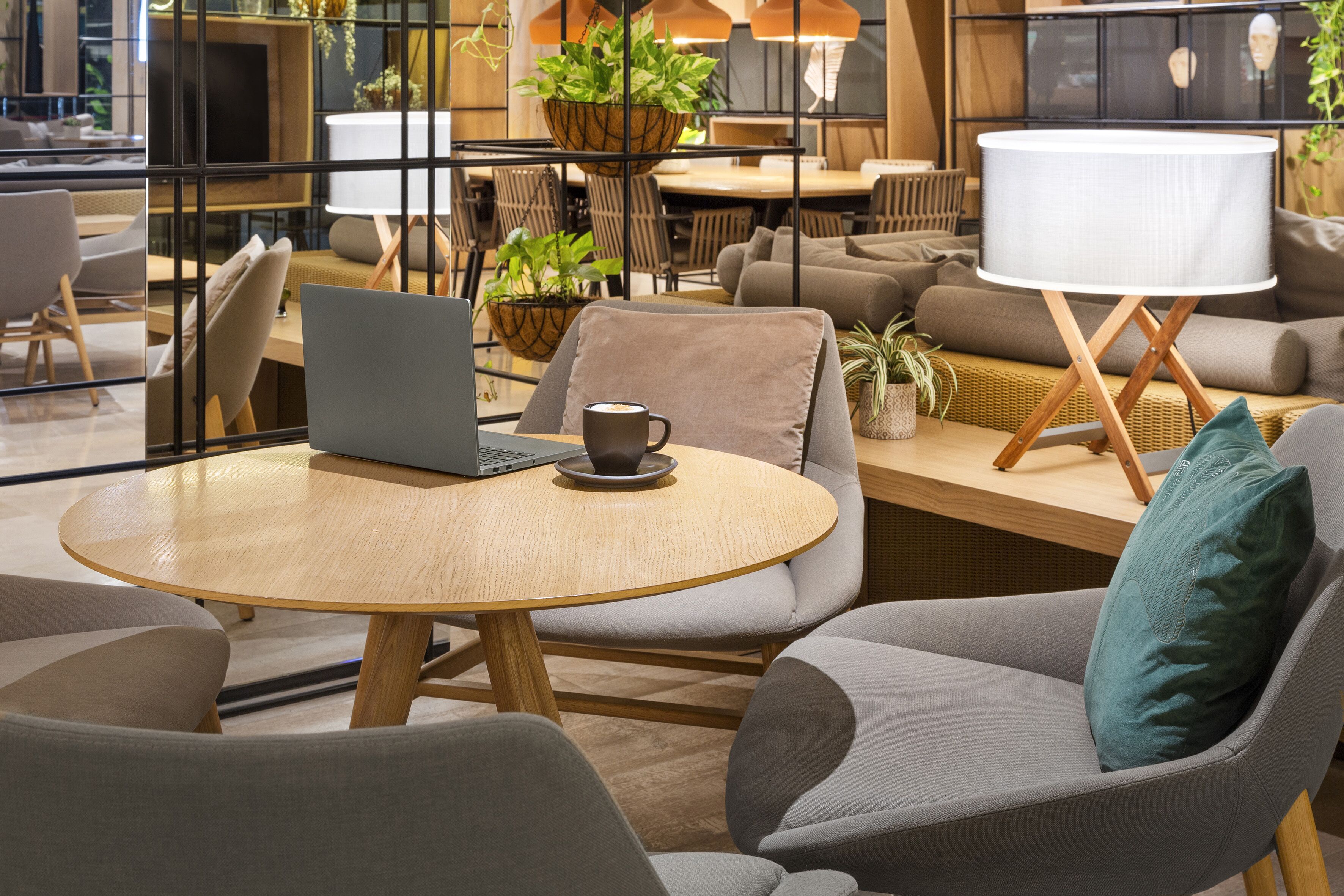 Et moderne loungeområde med runde borde, behagelige siddepladser og en bærbar computer på et bord.
