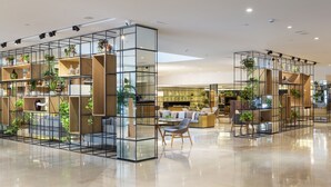 A modern interior with glass partitions, wooden shelves, and seating areas. - Melia Sevilla (Seville)