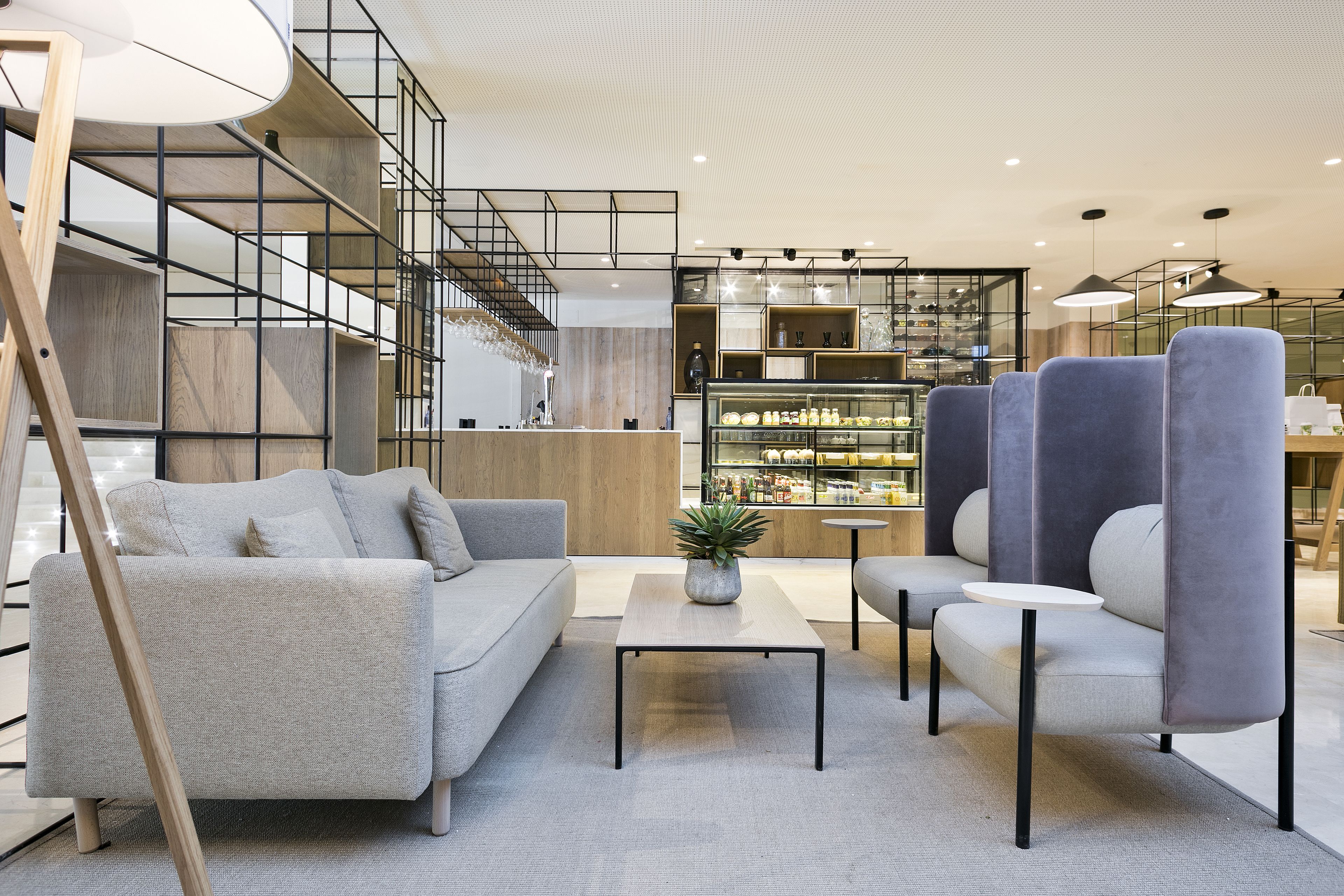 A modern interior with a sofa, armchairs, a coffee table, and a staircase.