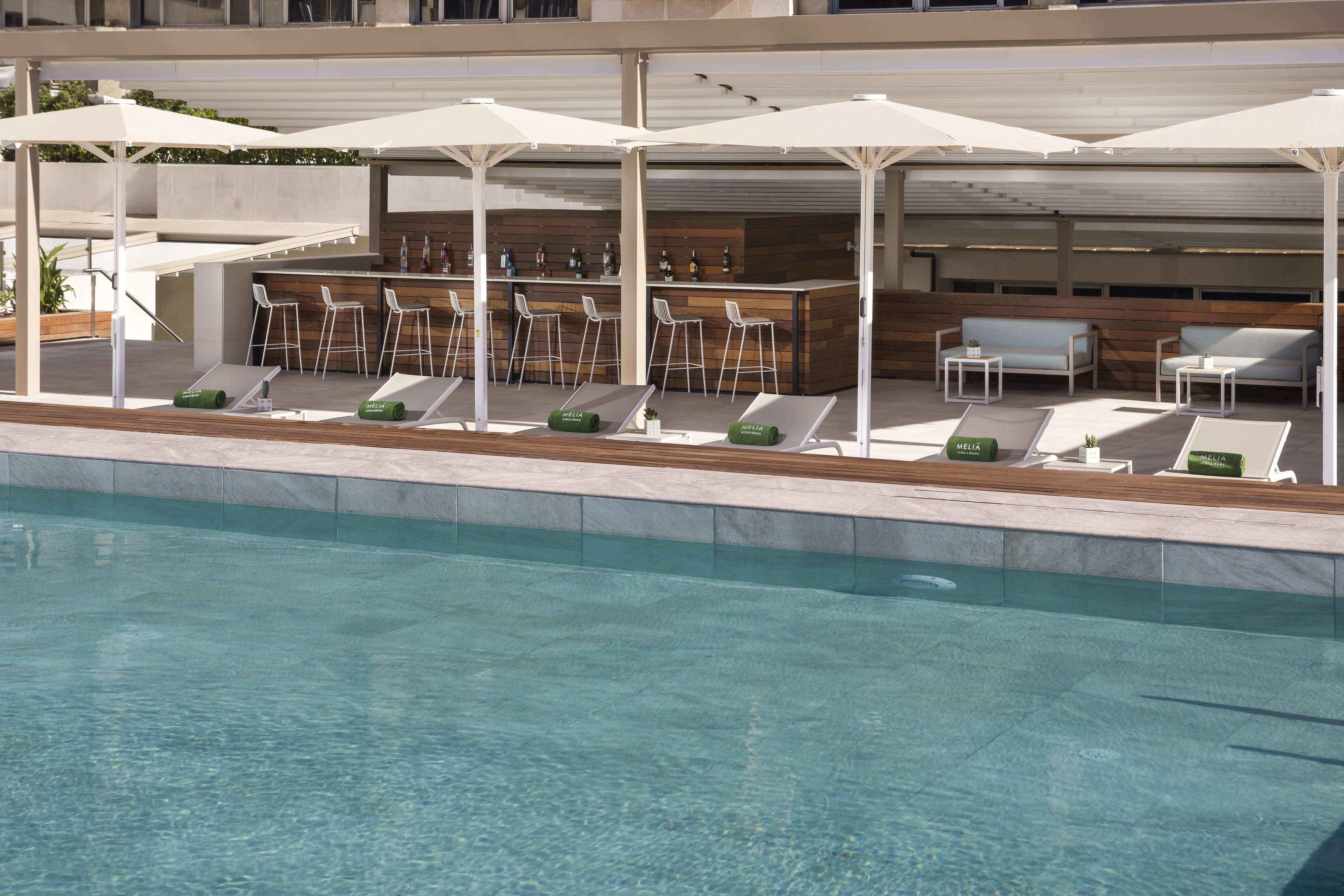 A poolside area with lounge chairs, bar area, and umbrellas.