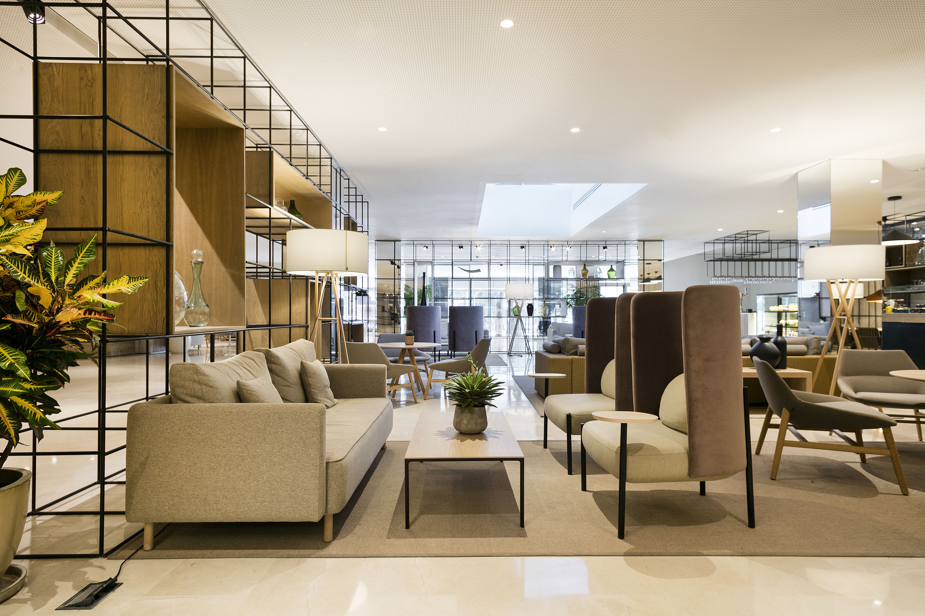 A modern interior with a sofa, armchairs, a coffee table, and a staircase.