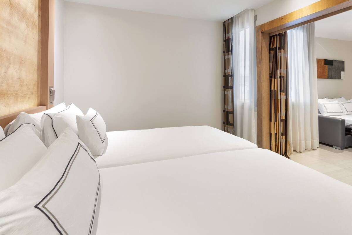 A modern hotel room with a large bed, a wooden headboard, and a view of a balcony.