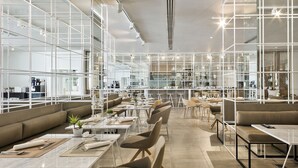 A modern restaurant with high ceilings, white metal partitions, and a variety of seating options including tables and booths. - Melia Sevilla (Seville)