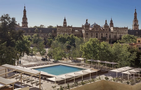 Una piscina al aire libre, sombrillas, sillones reclinables de piscina