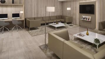 Una sala de estar moderna con un sofá modular, una mesa de centro, un televisor montado en la pared y un escritorio con dos monitores.