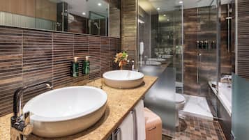 Een moderne badkamer met twee ruime wastafels, een glazen douchecabine en een toilet.