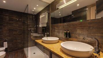 Un baño moderno con dos lavamanos, una ducha con mampara de vidrio y un espejo grande.
