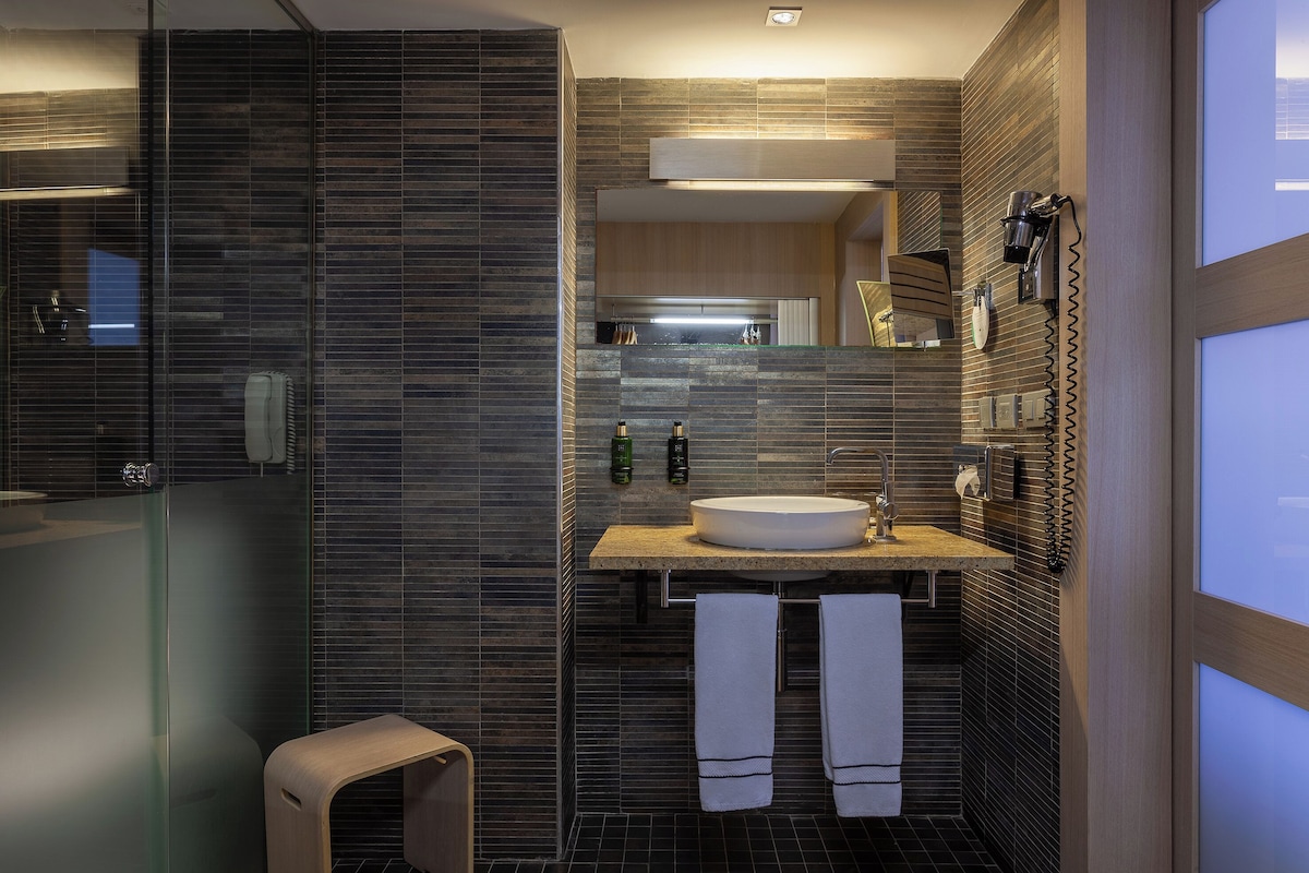 A modern bathroom with a glass shower enclosure, a wooden vanity with a sink, and a mirror above the vanity.