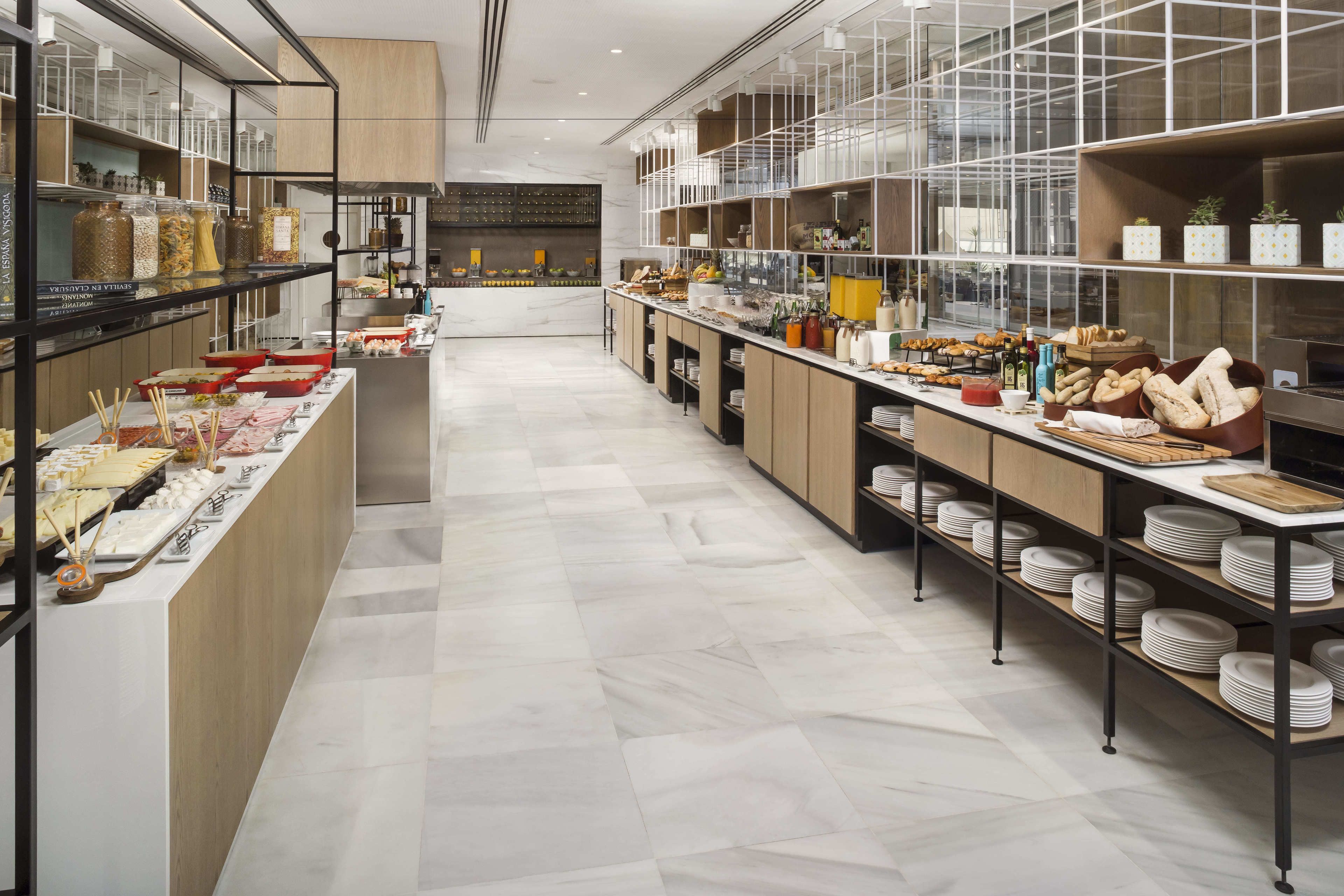 A modern kitchen with marble flooring, stainless steel appliances, and neatly organized shelves with various food items and kitchenware.