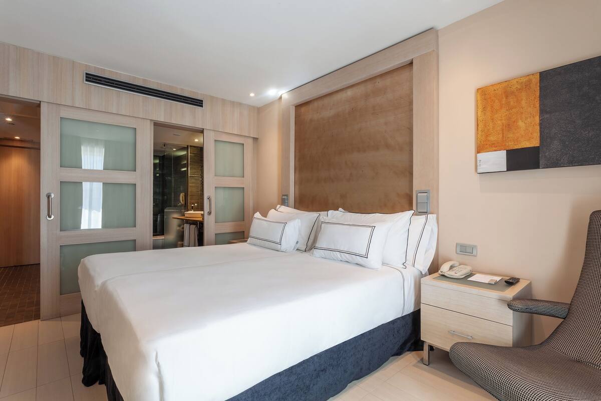 Una habitación de hotel moderna con una cama grande, un escritorio con teléfono y una silla.