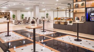 En moderne hotellobby med et centralt siddeområde, en reception og et udstilling af lokale produkter.