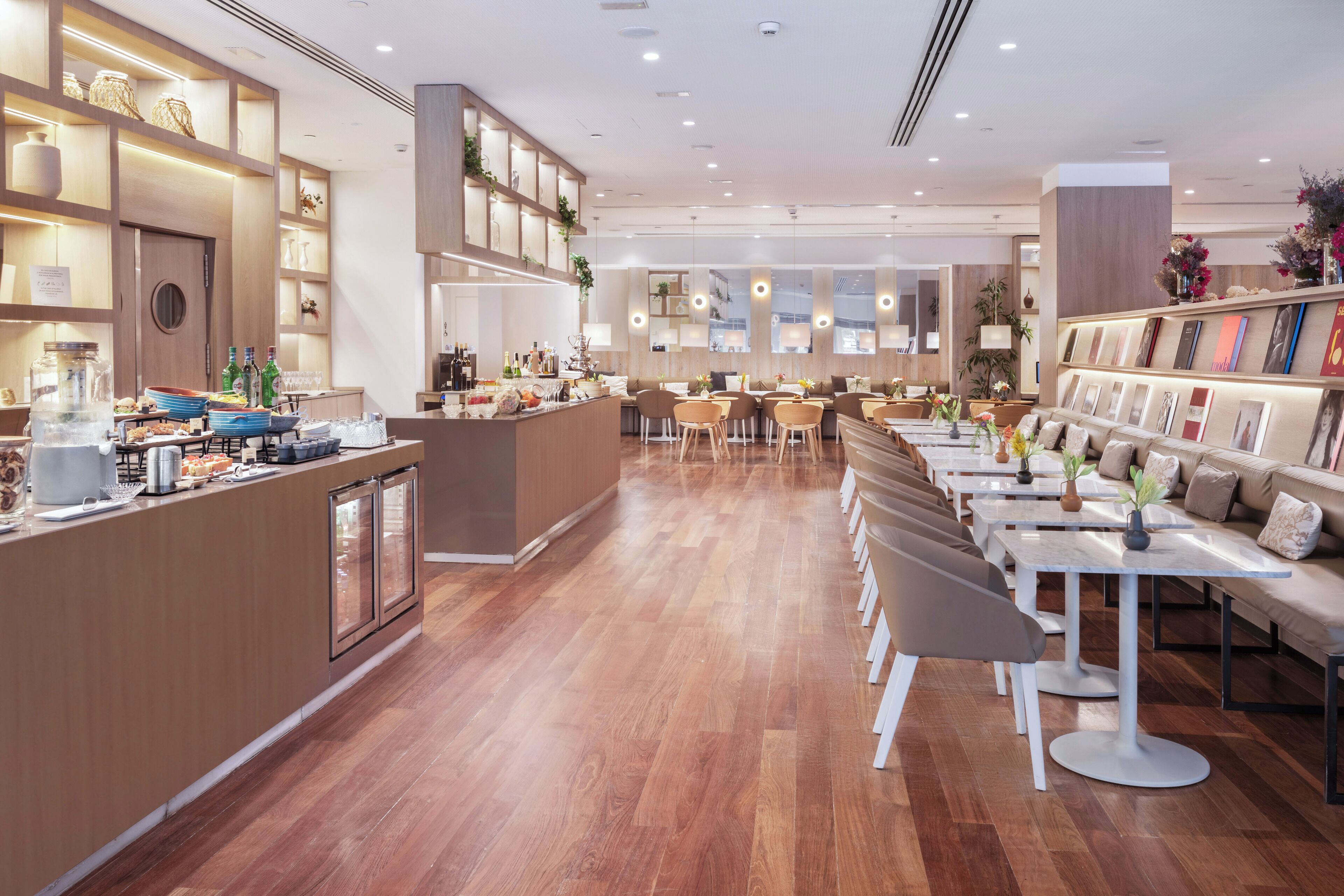 A modern restaurant with wooden flooring, a central bar area, and seating arrangements.