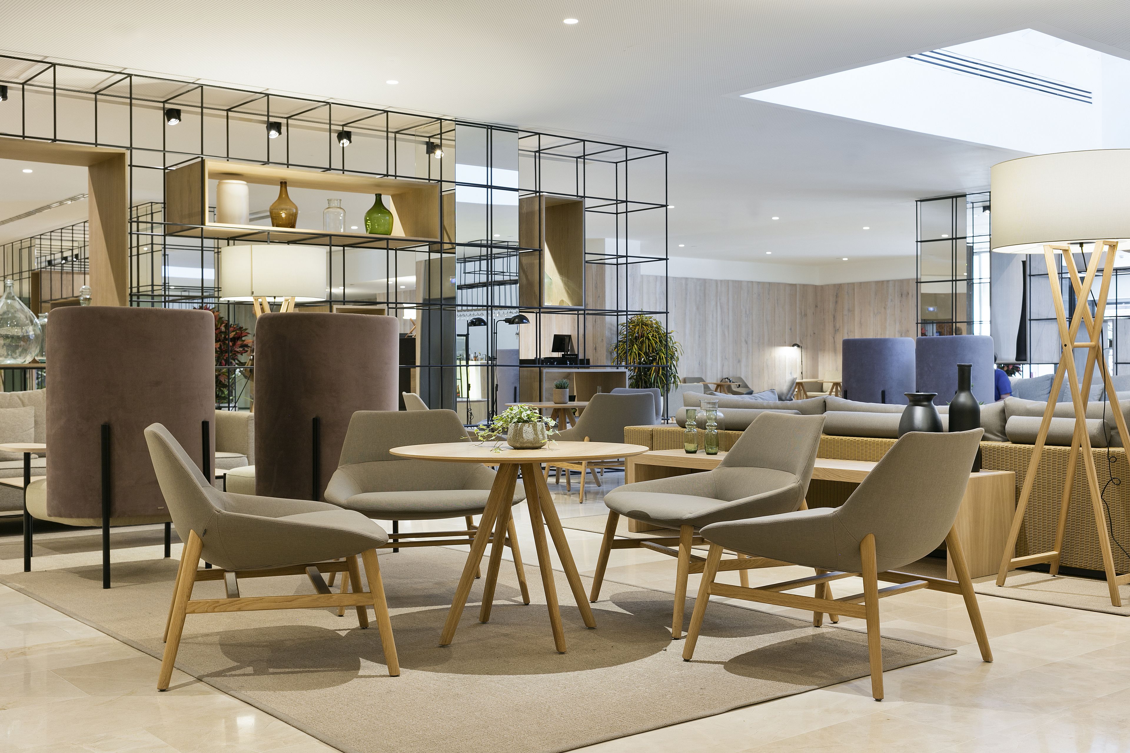 A modern interior with a central round table surrounded by chairs, a sofa, and a lamp.