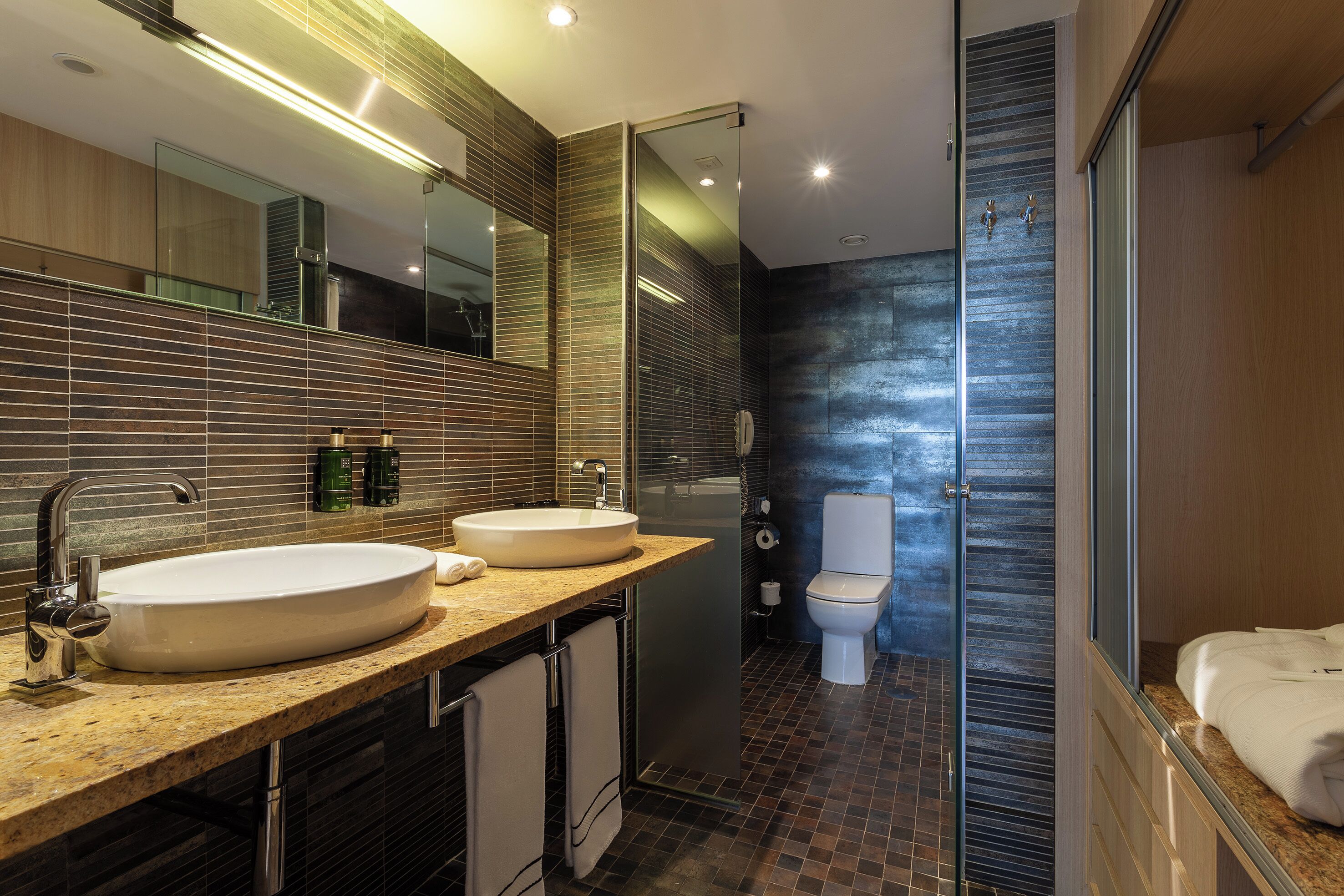 Un baño moderno con dos lavamanos, un espejo grande y una cabina de ducha de vidrio.