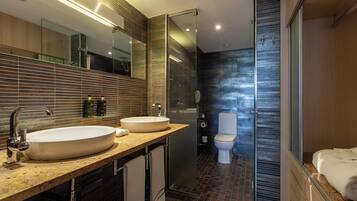 Un baño moderno con dos lavamanos, un espejo grande y una cabina de ducha de vidrio.