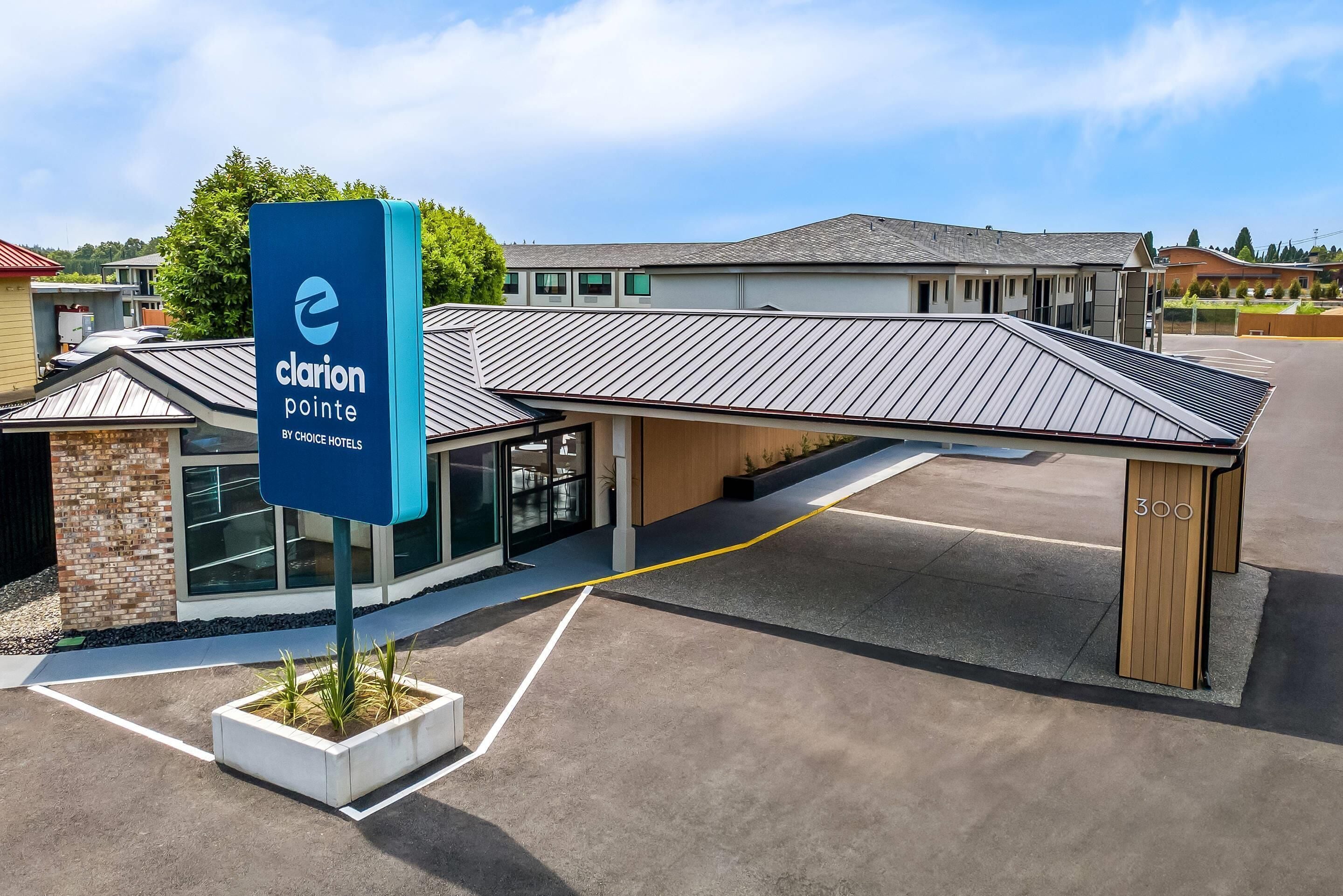 Un hôtel moderne, reconnaissable à son panneau « Clarion Pointe » bien visible, doté d’un parking couvert et d’un bâtiment au toit en pente.
