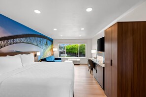 A modern hotel room with a large bed, a desk, a TV, and a mural of a bridge. - Clarion Pointe Mount Vernon - Burlington (Mount Vernon)