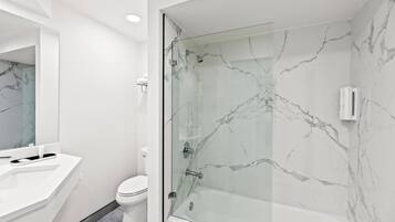 A modern bathroom with a glass-enclosed shower, a white sink, and a toilet.