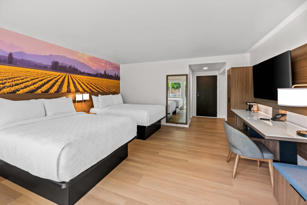 Una habitación de hotel moderna con una cama grande, un escritorio y un televisor.