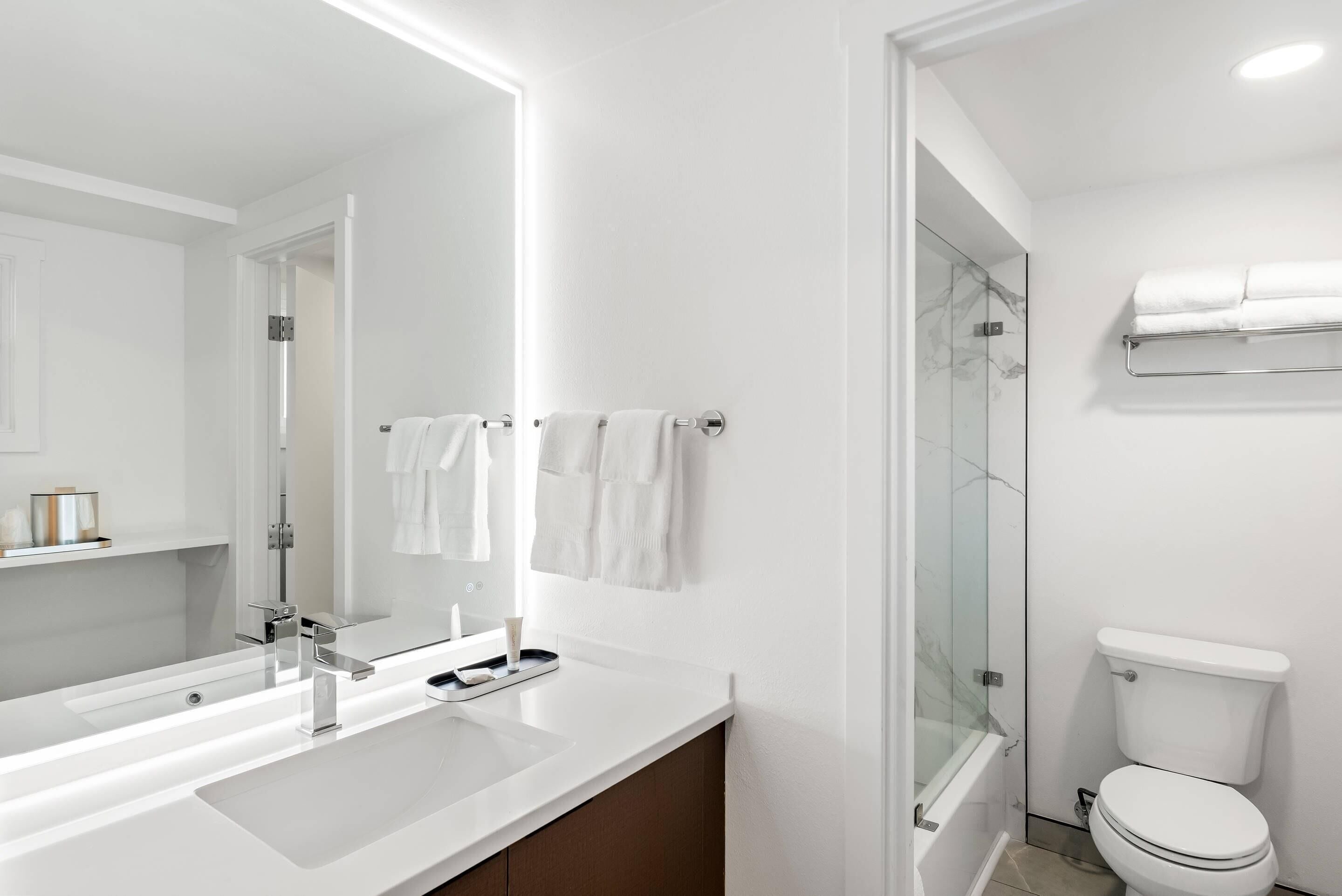 A modern bathroom with a white sink, mirror, and toilet.