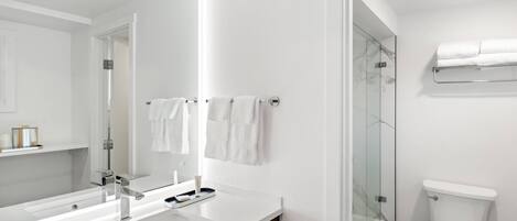 Un baño moderno con lavamanos, espejo y retrete blancos.
