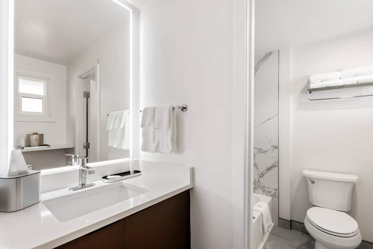 A modern bathroom with a white sink, a mirror, a towel rack, and a toilet.