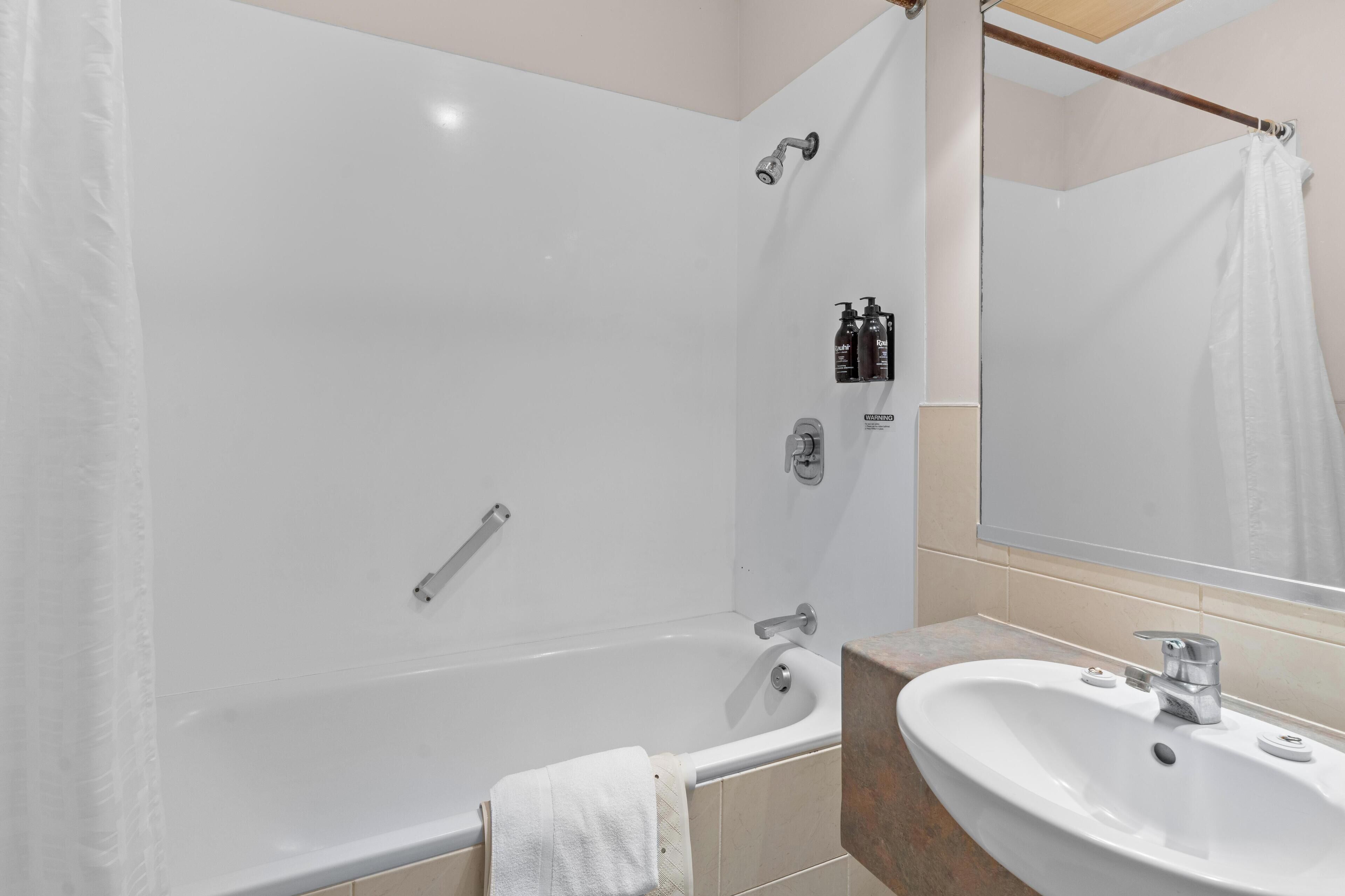 A modern bathroom with a bathtub, a sink, and a shower.