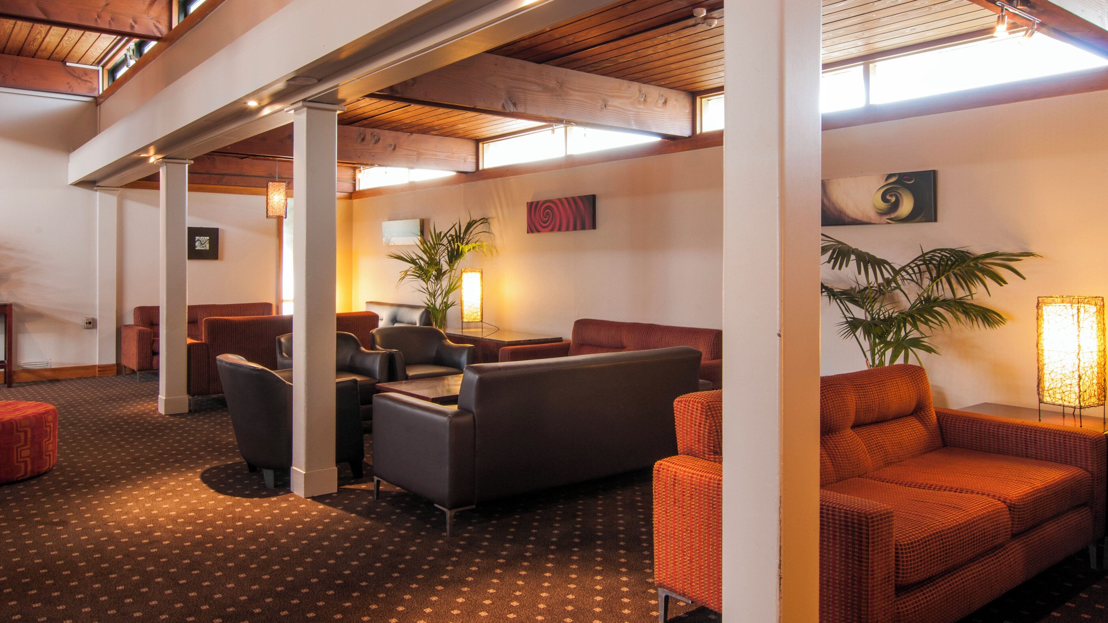 A hotel lobby with seating areas, a coffee table, and a plant.