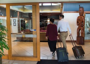 A hotel lobby with a reception desk, seating area, and a statue.