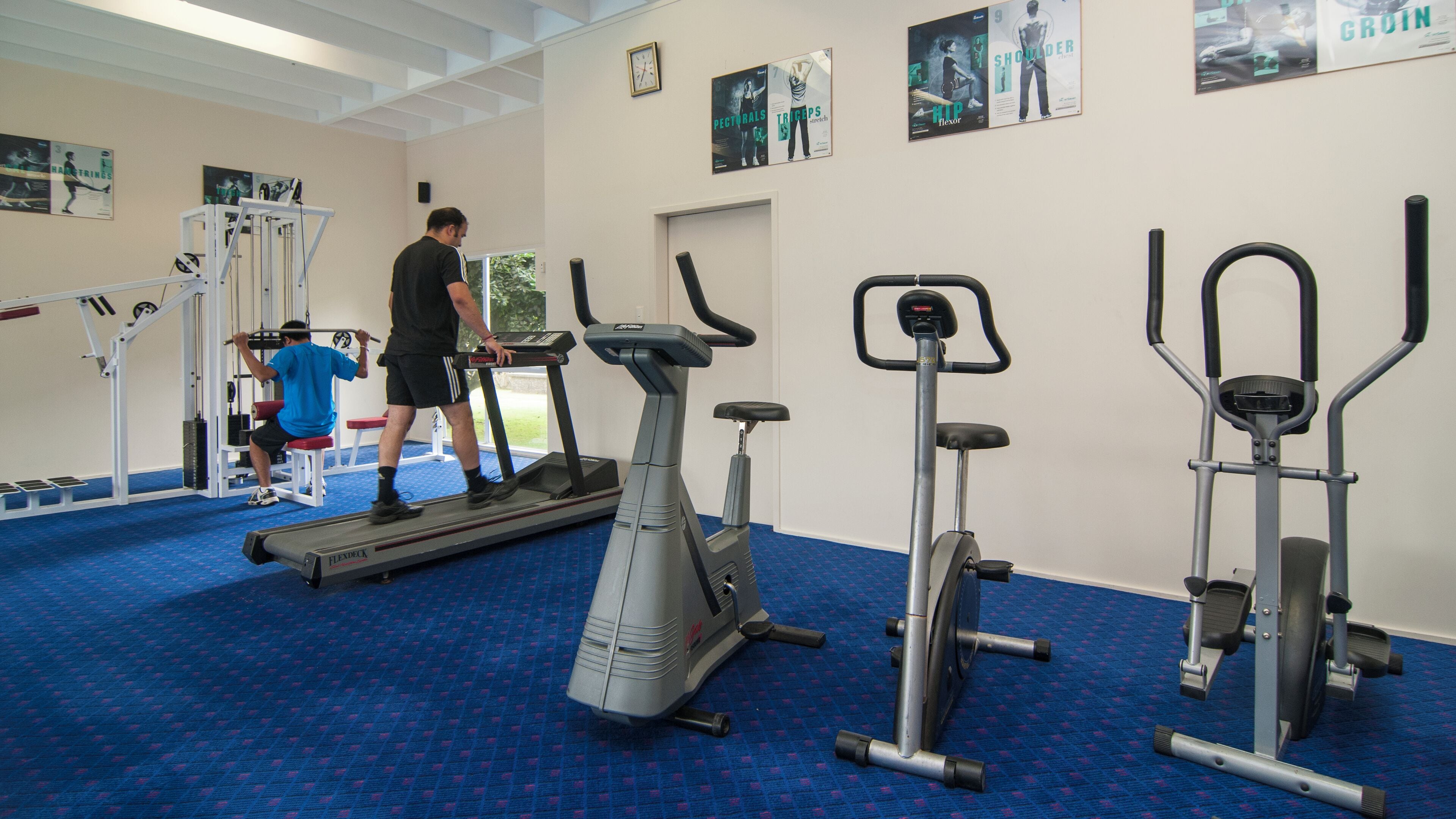 A gym with various exercise equipment including treadmills, an elliptical, and a stair climber.