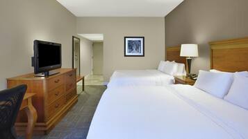 A hotel room with two beds, a television, a desk, and a chair.