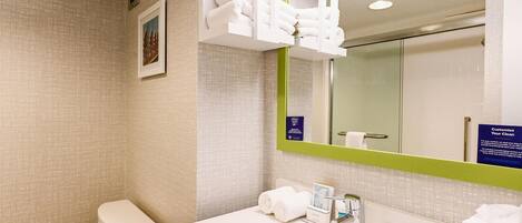 A bathroom with a toilet, sink, mirror, and towel rack.