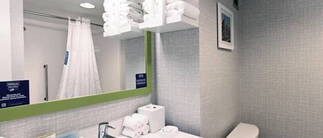 Un baño moderno con un espejo grande, lavamanos blanco y toallas ordenadas.