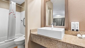 Un baño con lavamanos blanco, espejo y cortina de ducha.