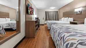 Habitación de hotel con dos camas, televisión, escritorio, lámpara y espejo.